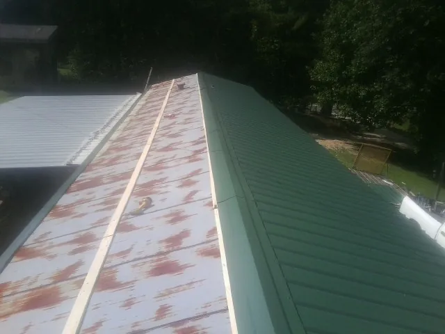 Old rusted panels beside newly installed green metal roofing — Wind Damage Roof Repair by Roofing Brothers in Leawood