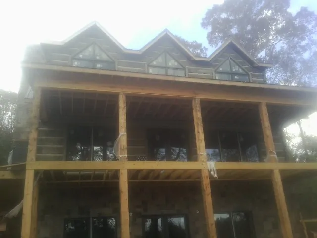 Dormers and porch framing on a large log home under construction — Roof Coating work by our crew in Leawood