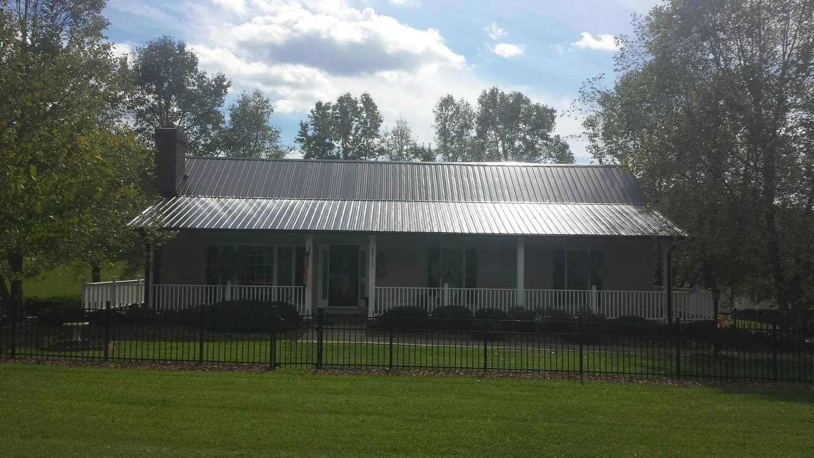 Gray metal roof on a brick ranch with a full width front porch — Gutter Guard Installation work by our crew in Leawood
