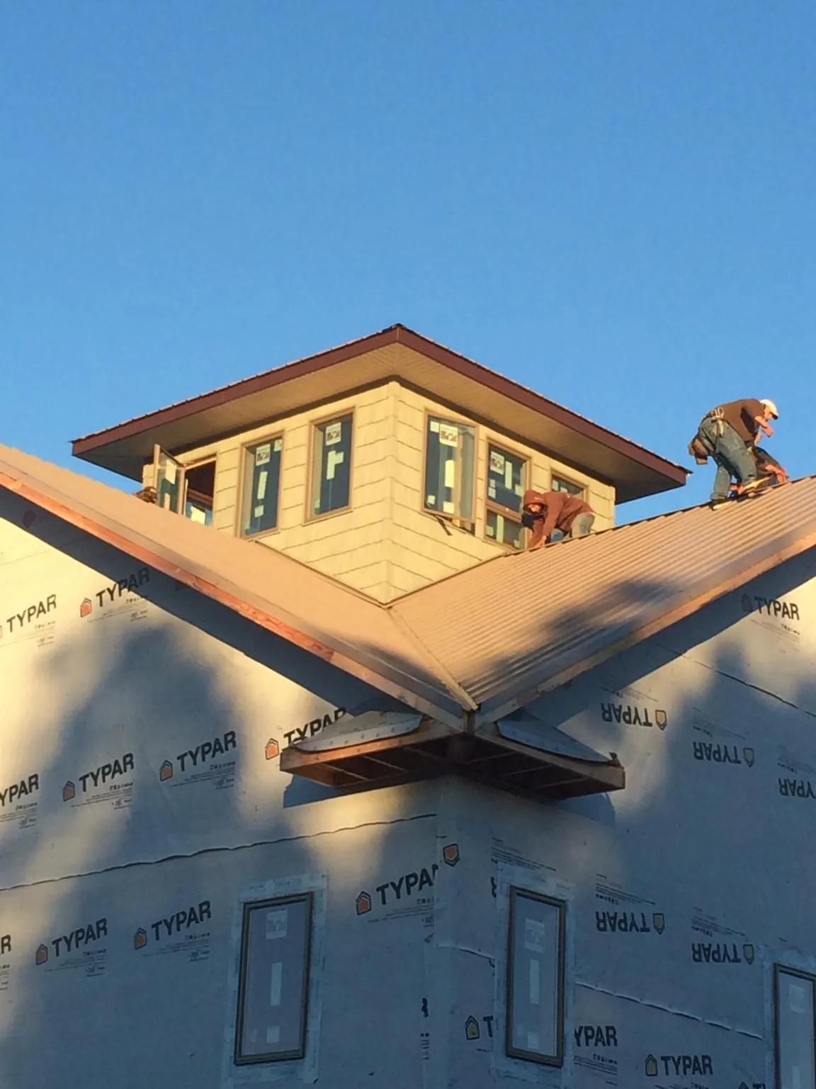 Roofers working around a rooftop cupola on a new metal roof at sunset — Roof Waterproofing in Leawood by Roofing Brothers